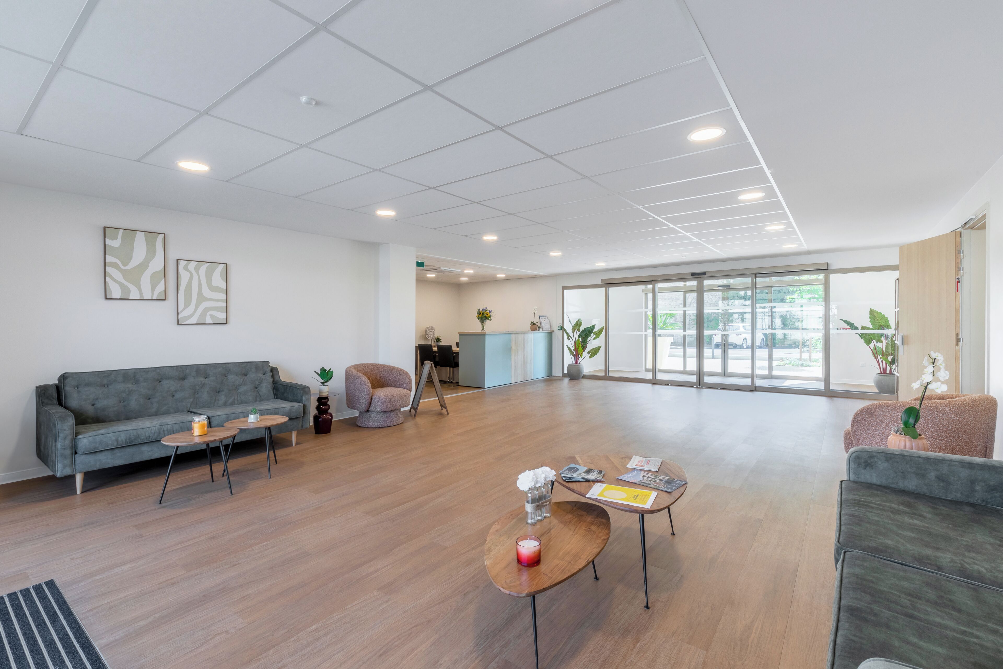 A spacious, modern interior with a grey sofa, a coffee table, and a seating area with a plant.