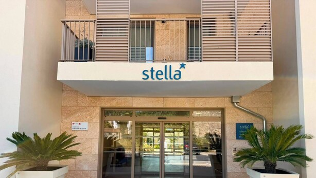 A building entrance with a sign reading 'stella' and a balcony above.