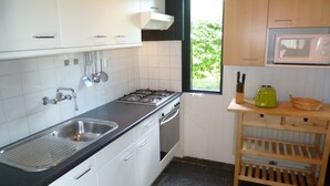 A kitchen with white cabinets, a stainless steel sink, a gas stove, and a microwave. - Detached Bungalow, Perfect for Water Sports and Nature Enthusiasts (Kamperland)