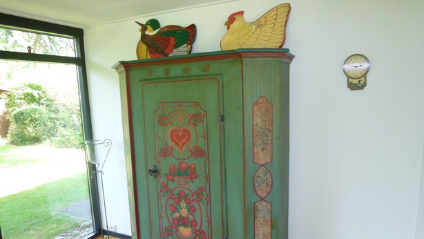 A green cabinet with decorative elements and a clock on the wall. - Detached Bungalow, Perfect for Water Sports and Nature Enthusiasts (Kamperland)