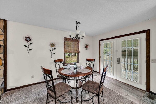 A dining area with a round table, four chairs, a chandelier, and decorative wall art.