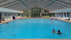 Une piscine intérieure dotée d’un toit couvert, de parois en verre transparent et de plusieurs couloirs de nage.