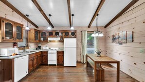 Un intérieur en bois comprenant une cuisine, une table à manger et des poutres apparentes au plafond.