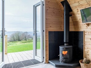 A modern log cabin with a large glass door leading to a deck, a black fireplace, and a television mounted on the wall. - The Lodge at Brambles Farm Sleeps 4 Hot Tub (Leek)