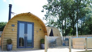 Una baita in legno con un'ampia entrata ad arco, una terrazza e una vasca idromassaggio.
