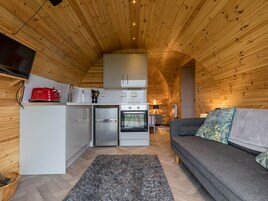 A compact, wooden interior with a kitchenette, a sofa, and a television.