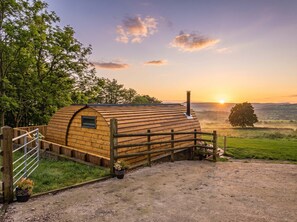 A wooden cabin with a sloped roof, surrounded by a wooden fence, and a gravel path leading to it. - The Lodge at Brambles Farm Sleeps 4 Hot Tub (Leek)