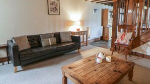 Ein Wohnzimmer mit einem dunklen Ledersofa, einem Holztisch, einem Holzstuhl mit Hummer-Kissen und einer Heizung.