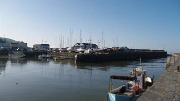 A harbor with boats docked, a stone quay, and buildings in the background.
