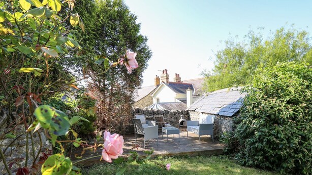 Ein Garten mit einer Terrasse, einer Steinmauer und einem Haus im Hintergrund.