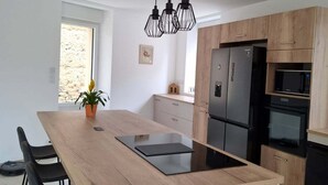 Eine moderne Küche mit einer zentralen Kochinsel, schwarzen Geräten und einer Holz Arbeitsplatte.