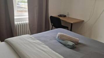 A hotel room with a bed, a desk, a chair, and a television.