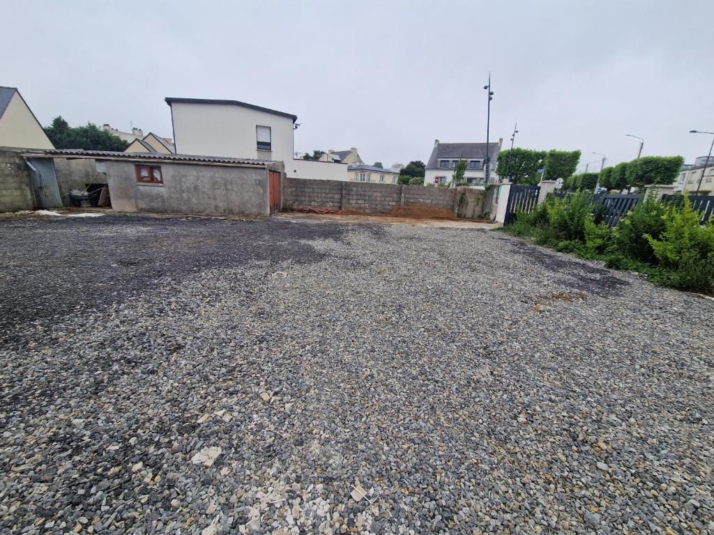 A gravel parking area with a building in the background.