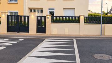 A residential street with a gated entrance, a road with directional arrows, and a blue street sign.