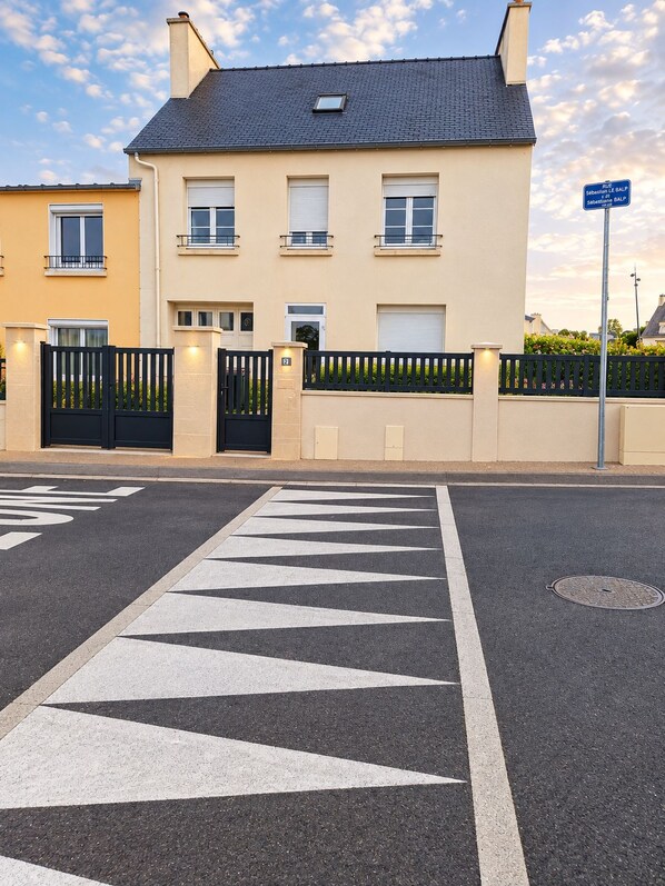 A residential street with a gated entrance, a road with directional arrows, and a blue street sign.