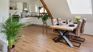 Eine moderne Küche mit weißen Schränken, einem Holztisch und einer großen Kühlpflanze.