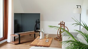 Ein modernes Wohnzimmer mit Flachbildfernseher, Holztisch und einer Couch.