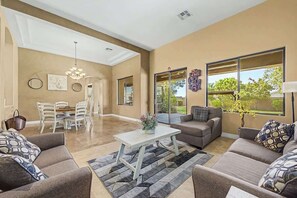 A spacious living room with a sofa set, a coffee table, and a dining area with chairs and a table. - Family Retreat • 6BR • Sleeps 13 • Parking (Phoenix)