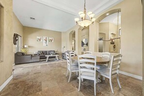 A spacious living area with a dining table, chairs, a sofa, and a chandelier. - Family Retreat • 6BR • Sleeps 13 • Parking (Phoenix)