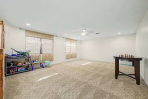 A spacious room with a carpeted floor, a ceiling fan, and a chess table. - Family Retreat • 6BR • Sleeps 13 • Parking (Phoenix)