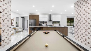 Eine moderne Küche mit Billardtisch, Barbereich und Blick ins Freie.