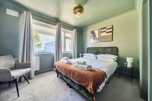 A hotel room with a bed, a chair, a bedside table, a lamp, and a window with curtains. - 2 Bedroom Apartment Sleeps 3 - Garden - Pets (St Ives)