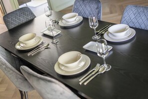 A dining table set with white plates, bowls, and cutlery, including forks, knives, and spoons. - 2 Bedroom Apartment Sleeps 3 - Garden - Pets (St Ives)