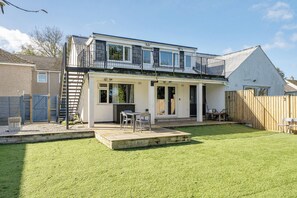 A two-story house with a balcony, a patio with outdoor furniture, and a fenced backyard. - 2 Bedroom Apartment Sleeps 3 - Garden - Pets (St Ives)