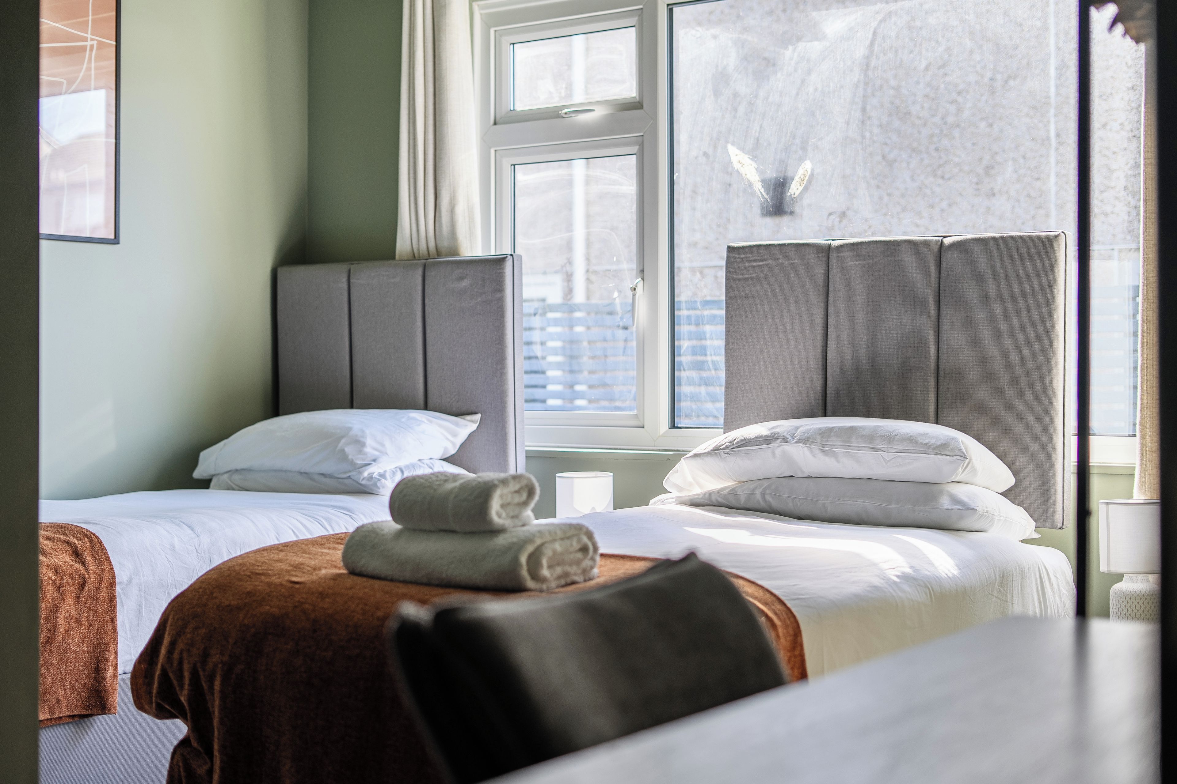 A hotel room with two beds, a window, and a view of the city.