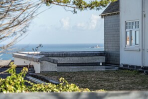 A coastal building with a concrete staircase leading to a deck overlooking the sea. - 2 Bedroom Apartment Sleeps 3 - Garden - Pets (St Ives)