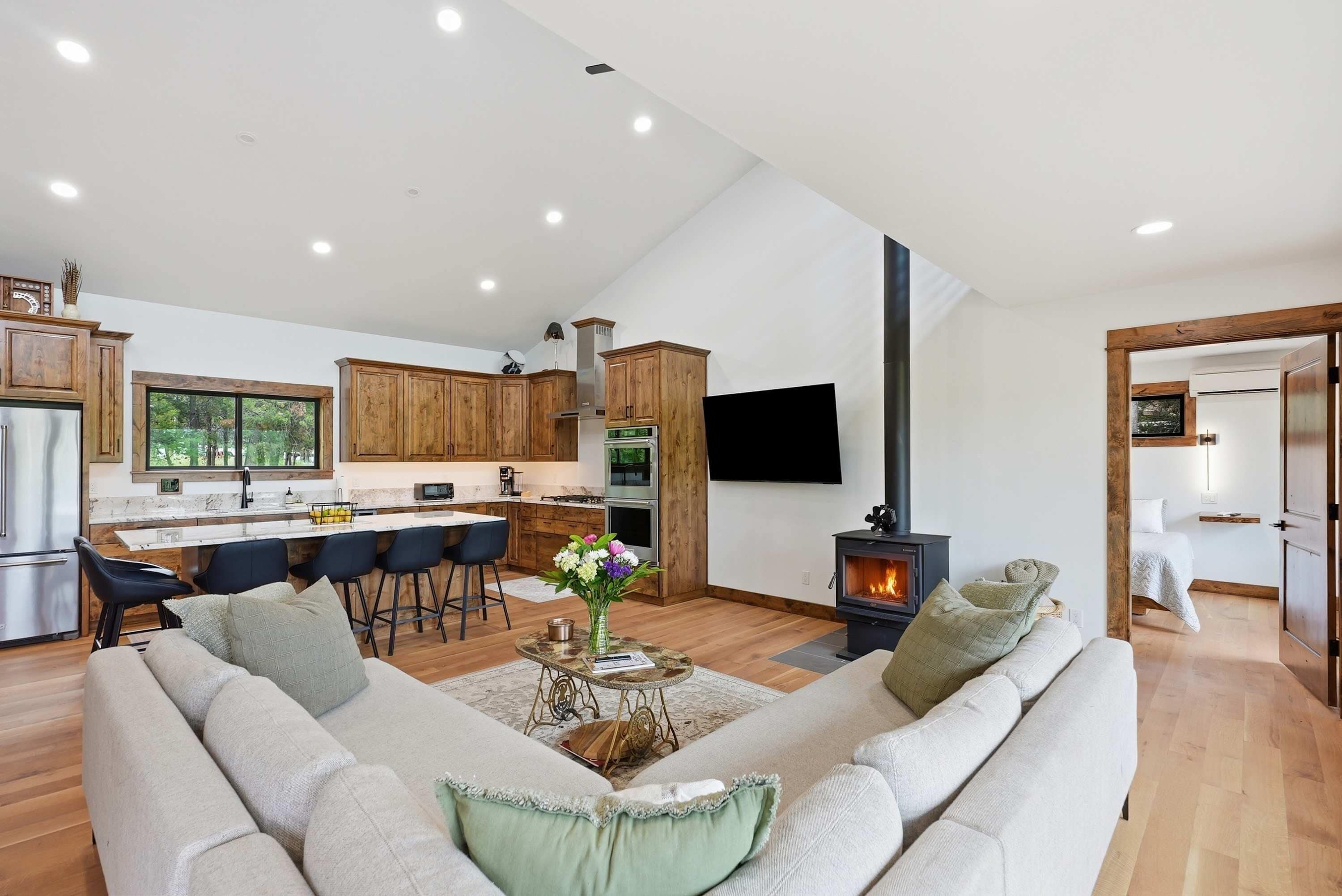A modern kitchen with wooden cabinets, a central island, and a dining area with bar stools.