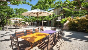 Une terrasse extérieure avec des tables et des chaises, entourée d’arbres et d’immeubles.
