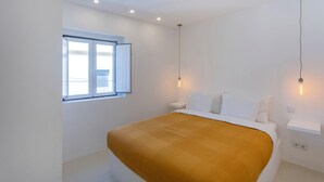 Une chambre à coucher comprenant un lit, une fenêtre, une table de chevet et un luminaire fixé au mur.