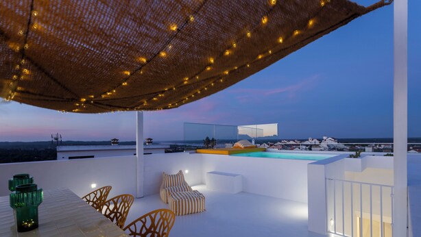 Une terrasse extérieure avec une table, des chaises, une piscine et une vue sur la mer.