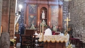 En kyrkas interiör med en stenmur, ett träaltare och religiösa statyer.