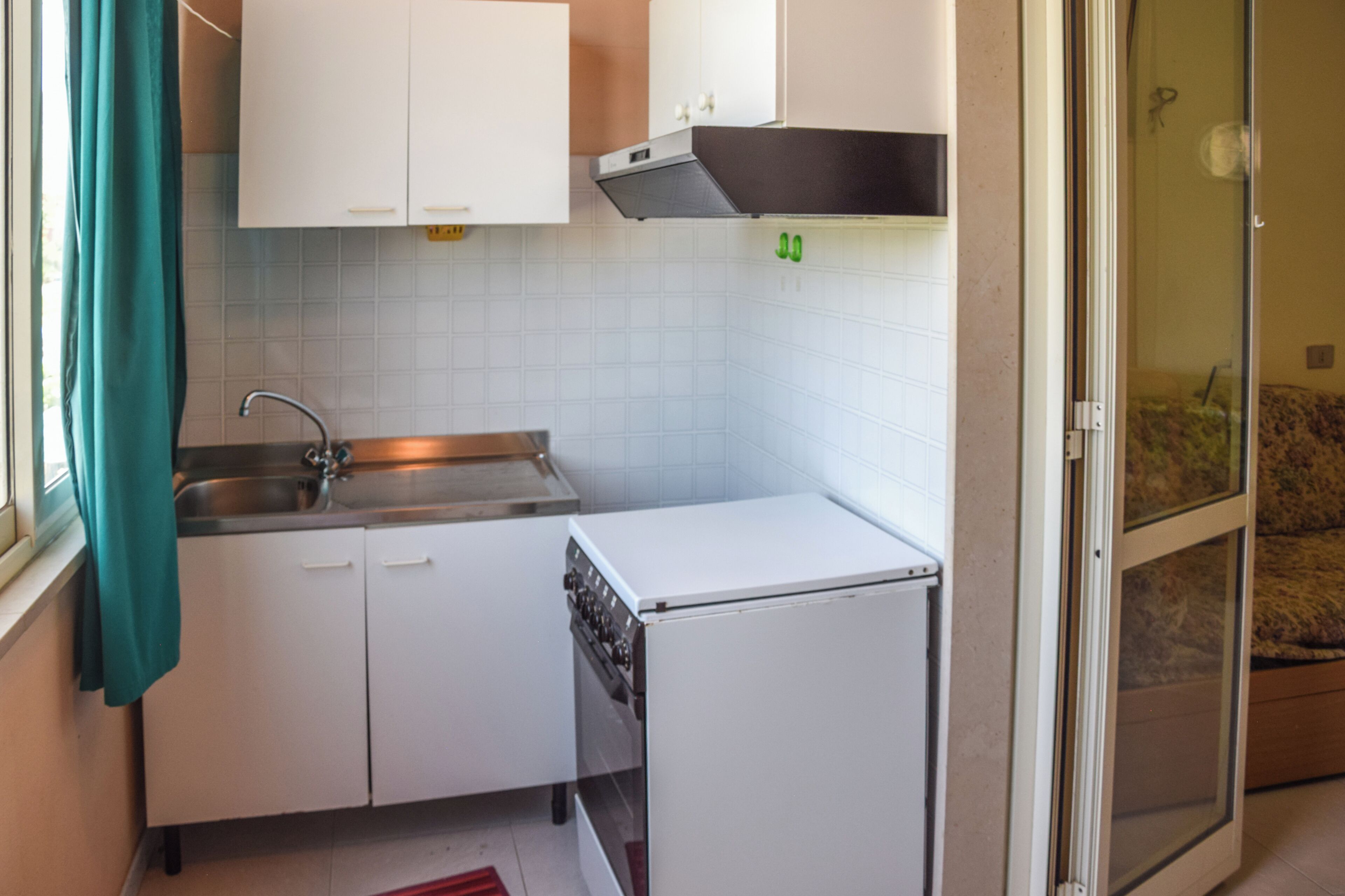 Eine kleine Küche mit weißen Schränken, einer Edelstahl-Spüle und einem eingebauten Backofen.