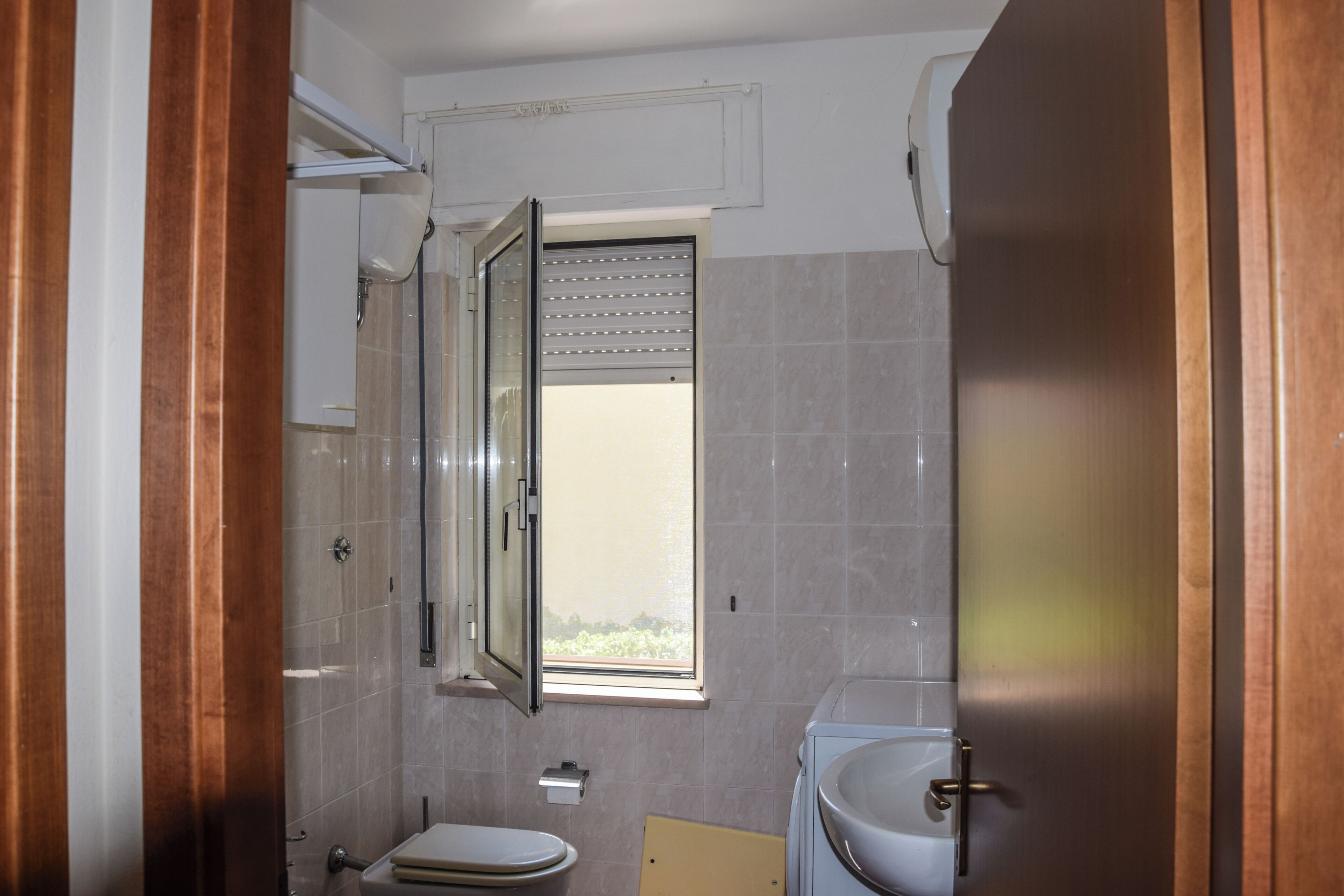 Ein Badezimmer mit Toilette, Waschbecken, Fenster und Dusche.