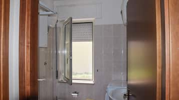 Ein Badezimmer mit Toilette, Waschbecken, Fenster und Dusche.