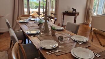 Een eettafel voor vier personen, compleet met stoelen, een kroonluchter en uitzicht op het groen.