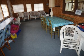 Una habitación con una mesa azul, sillas blancas, una lámpara y un letrero en la pared.