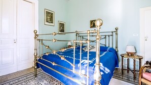 A room with a bed, a door, and a small table with a lamp.