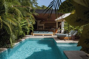 A pool area with a lounge chair, a sofa, and a dining area with a ceiling fan. - Casa Península 2BR Villa Playa Pelada, Nosara | ATV available (Nosara)
