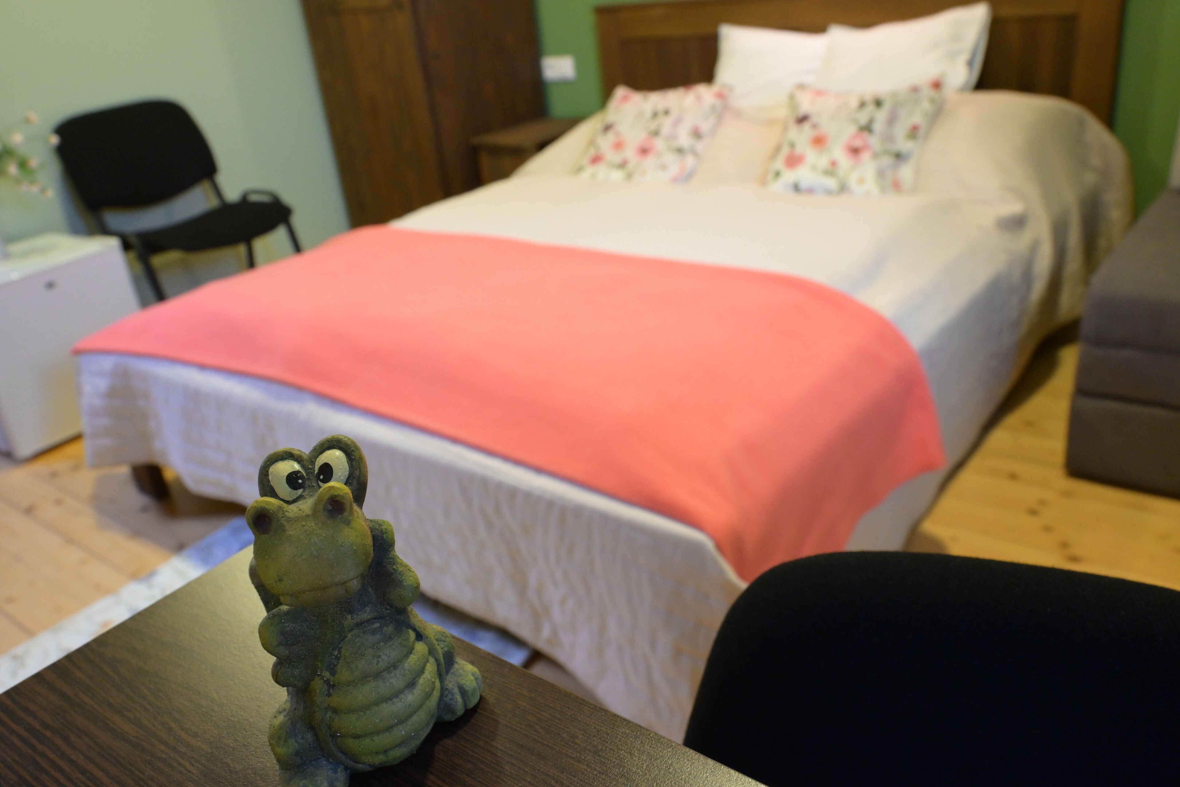 A bed with a pink blanket, a wooden headboard, and floral pillows.