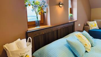 Un dormitorio con ventana, una mesita de noche, una cama con colcha acolchada y una lámpara de pared.