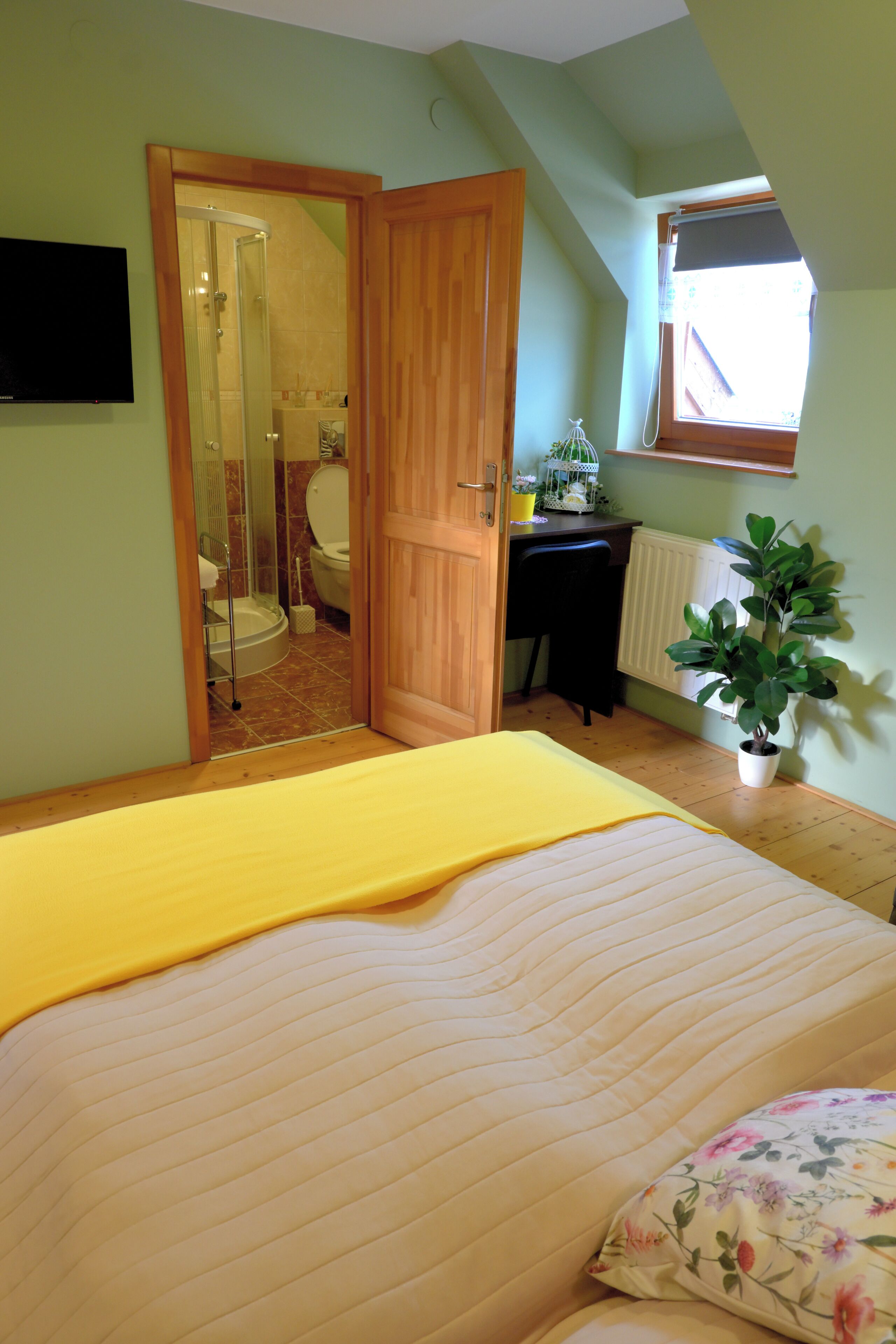 Un dormitorio con cama, escritorio, planta en maceta y zona de ducha.