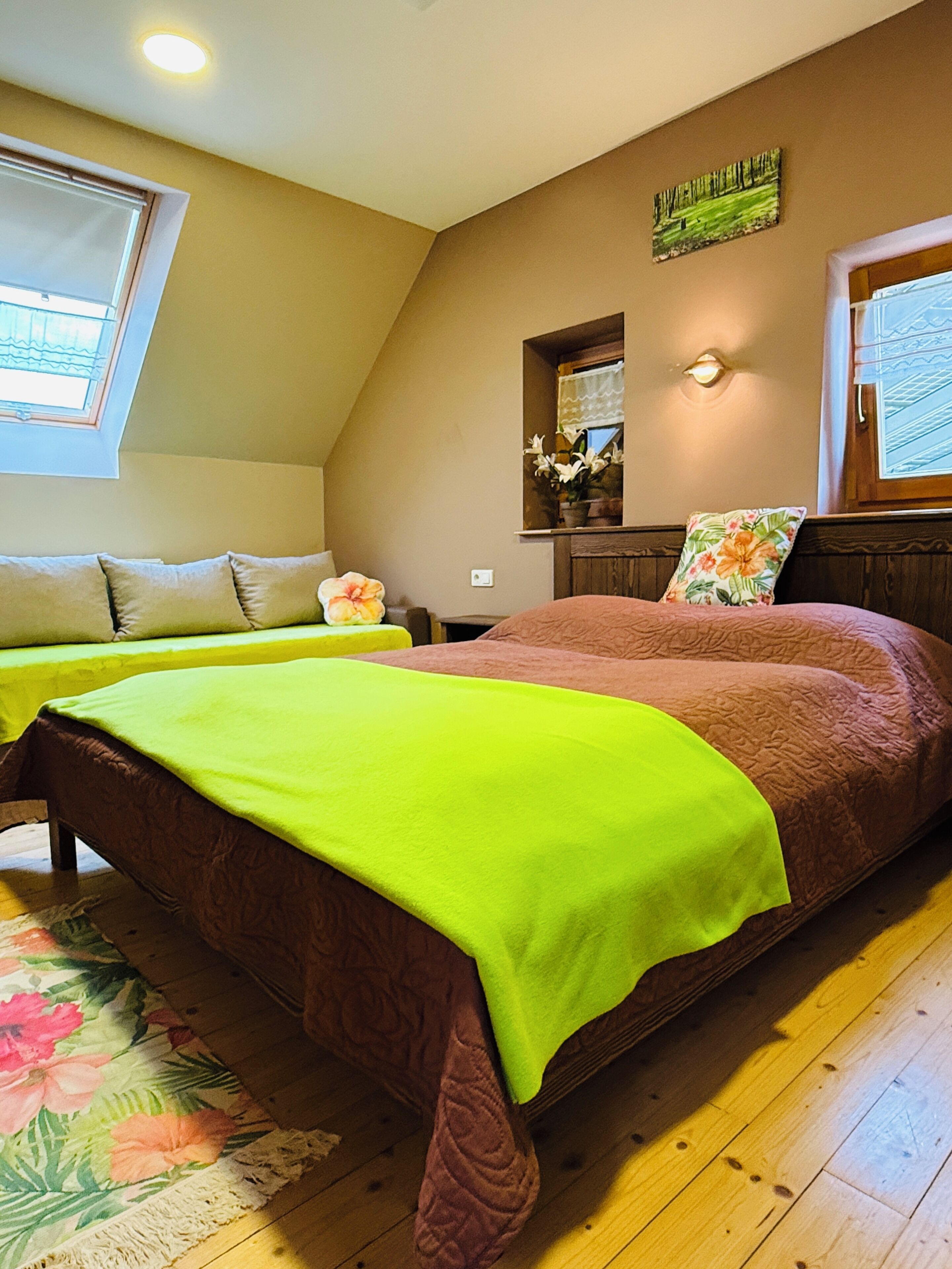 A bedroom with two beds, a window, a mirror, and a floral rug.