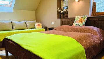 A bedroom with two beds, a window, a mirror, and a floral rug.