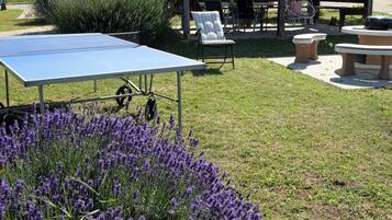 Een buitenruimte met een tafeltennistafel, zitplaatsen en een overdekte pergola.