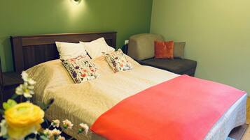 A bedroom with a bed, a nightstand, a chair, and a wall-mounted light.