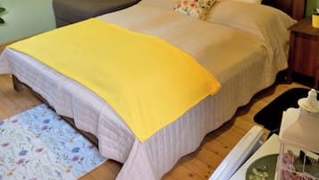 Un dormitorio con una cama, una mesita de noche, una lámpara de pared y una pared verde.